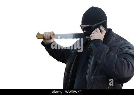 bandit with a machete in a black mask talking on the phone on an white isolated background Stock Photo