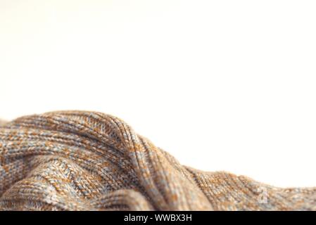 Mottled beige knitted woollen sweater on white background. Texture detail close up. Negative space. Stock Photo