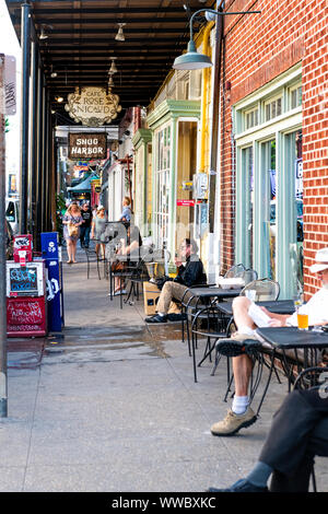 New Orleans, USA - April 22, 2018: Frenchmen street in French Quarter in Louisiana city with people sitting at outdoor sidewalk cafe bar or restaurant Stock Photo