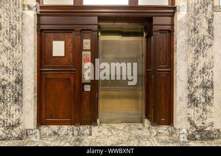 Old elevator with metal doors and wood grain paneling Stock Photo