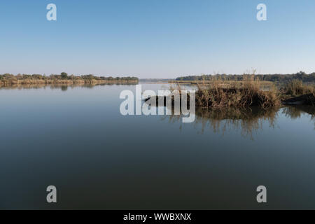 Tranquil Landscape with Calm Okavango River Water and Grass in Namibia, Africa Stock Photo