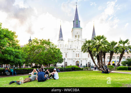 New Orleans, USA - April 22, 2018: Old town Louisiana town city with St Louis cathedral, water fountain in Jackson Square park with people lying down Stock Photo