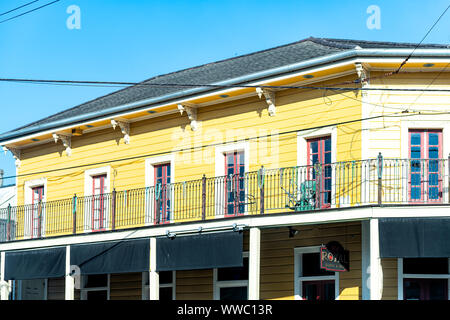 New Orleans, USA - April 23, 2018: Old town Royal street in French Quarter, Louisiana with sushi bar and restaurant and colorful yellow house balcony Stock Photo