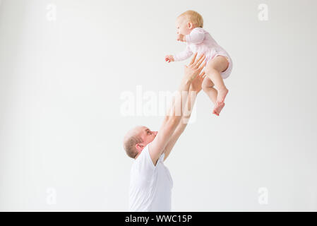 Father lifting baby girl. Happy father picks up and throws his lifting a small child. Home atmosphere, happy family laughing baby Stock Photo