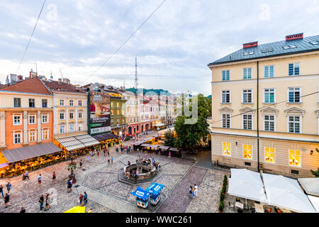 Lviv, Ukraine - July 30, 2018: Aerial view on Old town market square, people walking by colorful architecture, Neptune fountain and restaurants in sum Stock Photo