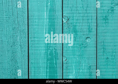 Old painted turquoise wooden fence. Cracked wood timber, blue shabby planks, green flaky grunge background. Oak table. Rustic weathered texture. Natur Stock Photo