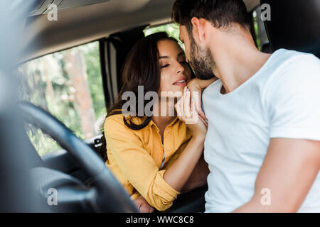 selective focus of young woman with closed eyes sitting near bearded man in car Stock Photo