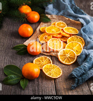 Dried oranges, fresh tangerines and Christmas tree on a old wooden table Stock Photo
