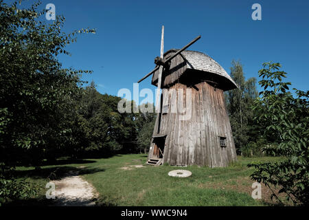 Open Air Village Museum in Lublin, Poland, 09/04/2019. Historic wooden windmill with roof made of wood against blue sky Stock Photo