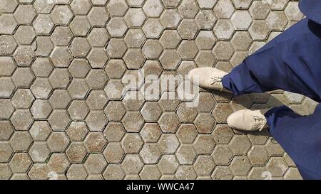 Wet paving stones with two legs in grey shoes. Stock Photo