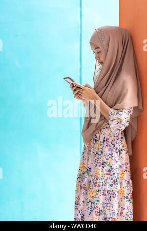 Young Adult Asian Thai Muslim university college student stand and using smart mobile phone. Unising for online education and technology concept Stock Photo