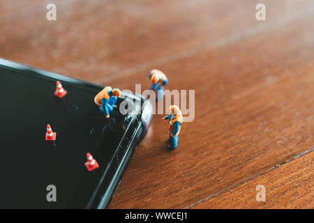 Miniature people Construction worker  repair smartphone using as background Maintenance concept and repair concept with copy space for your text or de Stock Photo