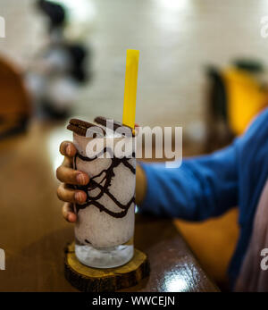 Hands holding homemade milkshake with cookies on the table Stock Photo