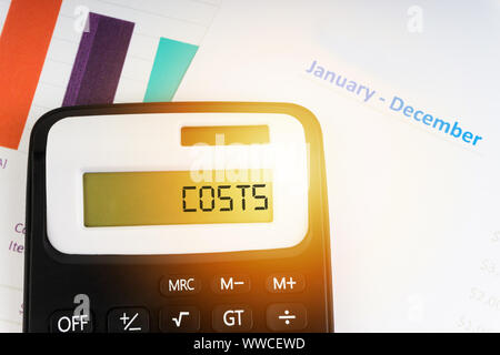 A calculator with the word COSTS on the display. Selective focus and crop fragment Stock Photo