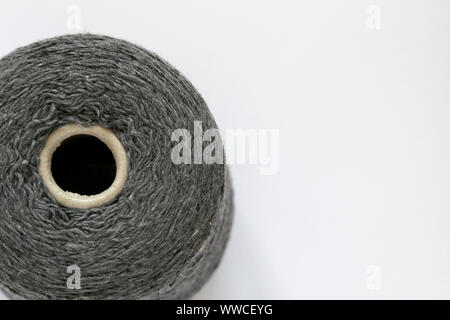 Bobbin of grey threads for hand and machine knitting close-up. Background top view, space for text. Stock Photo