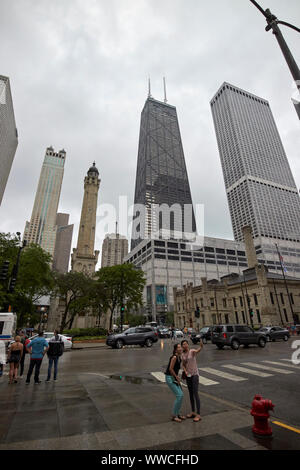 asian tourists taking selfie on north michigan avenue magnificent mile on a wet overcast day in Chicago Illinois USA Stock Photo