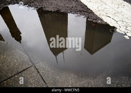 reflection of john hancock tower 875 north michigan in rainwater puddle on magnificent mile on a wet stormy overcast day Chicago Illinois USA Stock Photo