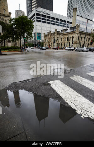 reflection of john hancock tower 875 north michigan in rainwater puddle on magnificent mile on a wet stormy overcast day Chicago Illinois USA Stock Photo