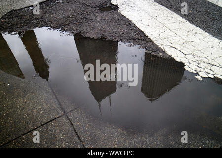 reflection of john hancock tower 875 north michigan in rainwater puddle on magnificent mile on a wet stormy overcast day Chicago Illinois USA Stock Photo