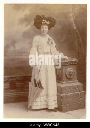 Original, clear, Edwardian Studio portrait photograph of fashionable glamorous Edwardian lady wearing a summer outfit, elaborate hat adorned with many feathers, holding a parasol, circa 1903, U.K. Stock Photo