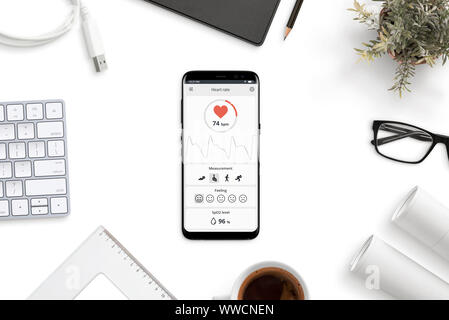 Measuring heart rate, beats per minute app on modern smart phone on office desk concept. Stock Photo