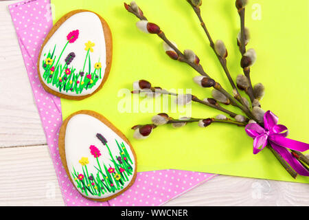 Gingerbread Easter eggs along with a willow twig on yellow and white geometric background .Easter background . Easter Trend colors Stock Photo