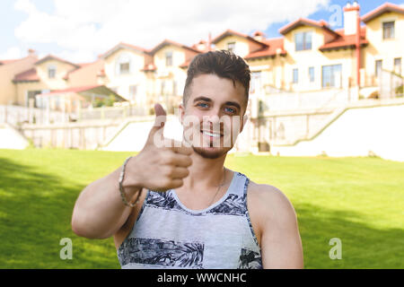 Attractive resting man with thumb up. beautiful cottages in the background Stock Photo
