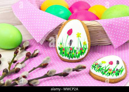 Easter background with Easter eggs and a willow twig. Gingerbread Easter and colored eggs with willow twig on wooden background. Easter Trend colors Stock Photo