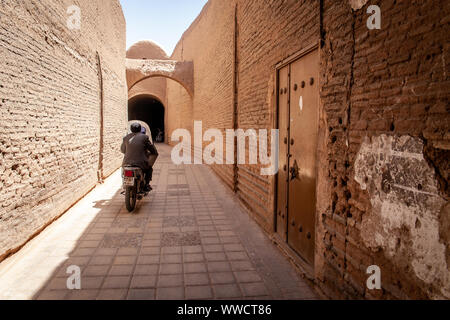 A man driving his motorbike in a little street of Shiraz, Iran Stock Photo