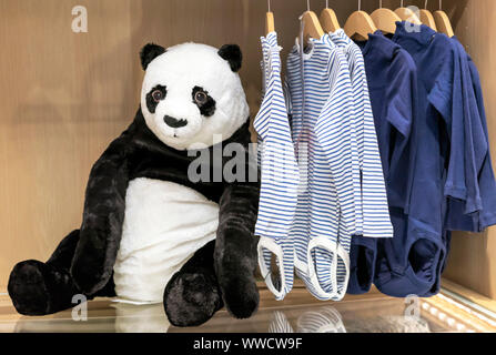 Soft toy panda bear on the background of children's clothing. Stock Photo