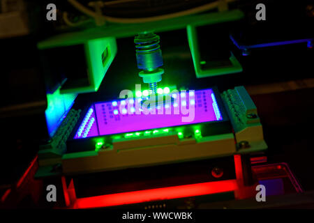 Pick and place machine picking up a component and recognize it with camera under green, blue and red lights Stock Photo