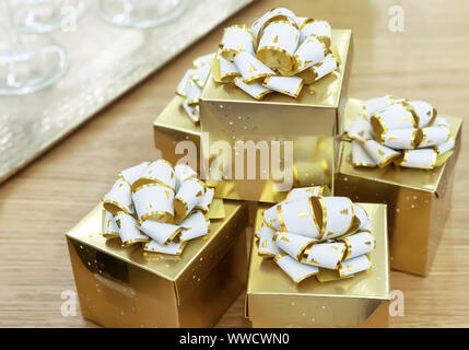 Golden gift boxes with white bows on a wooden table. Stock Photo