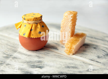 Honeycombs and ceramic Pot of honey and white flowers at the wooden table Stock Photo