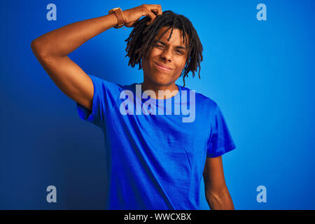 Afro american man with dreadlocks wearing t-shirt standing over isolated blue background confuse and wonder about question. Uncertain with doubt, thin Stock Photo
