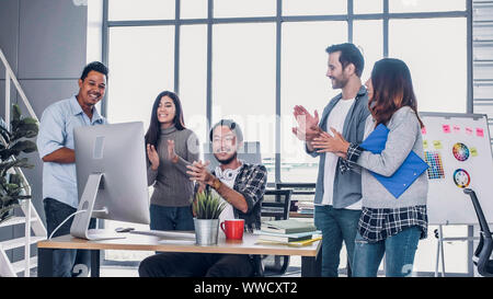 Creative director team applause for good solution of project with designer at table with desktop computer.discussion idea in creative office Stock Photo