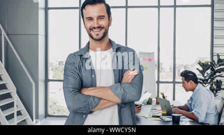 portrait of man creative director cross arm smile and looking at camera in modern office Stock Photo