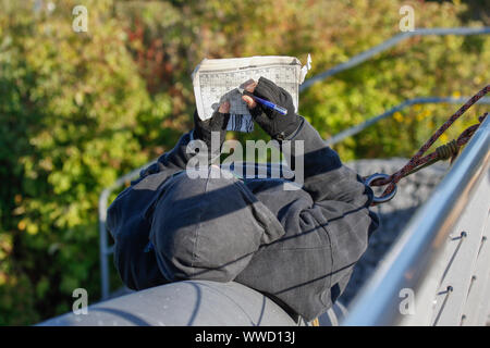 Frankfurt, Germany. 15th Sep, 2019. A protester lies on a bridge, doing a cross-word puzzle. Several hundred activists protested outside the 2019 Internationale Automobil-Ausstellung (IAA) against cars and for a change in traffic policies. They blocked several entrances to the exhibition. (Photo by Michael Debets/Pacific Press) Credit: Pacific Press Agency/Alamy Live News Stock Photo