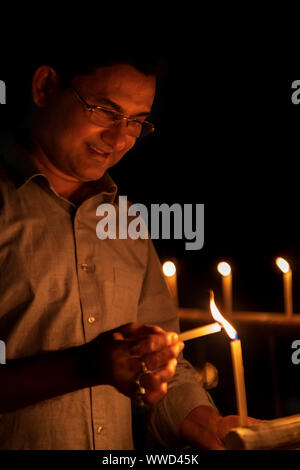 Indian Man lighting up candles at night on Diwali kali puja or pooja - an Indian Hindu festival of lights. Stock Photo