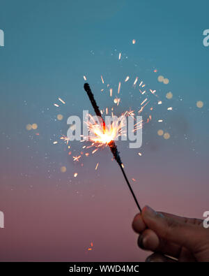Happy Diwali or New Year or Birthday sparkler celebration. Background picture for man holding burning sparkler in hand at night. Stock Photo