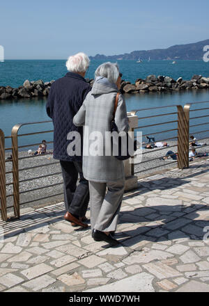 retired couple walking arm in arm along the seafront Stock Photo