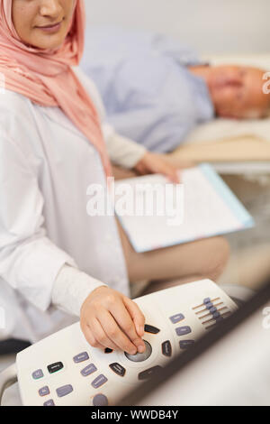 Closeup of young Arab female doctor performing ultrasound exam on senior patient in medical clinic, copy space Stock Photo