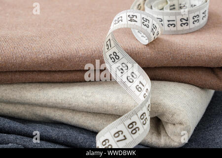 Stack of knitted multocolored fabrics closeup and measuring tape. Stock Photo