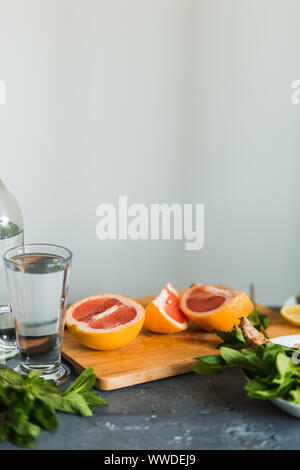 Juicy grapefruit pieces with fresh mint, a bottle of soda water on the kitchen table on a gray background, closeup. Summer, drinks, Mojito and lemonad Stock Photo