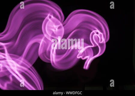 Neon pink flamingo LED lamp with wave in motion as blurred abstract background on black. Stock Photo