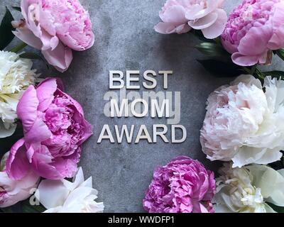 Peonies on a grey background around the words Best Mom Award Stock Photo
