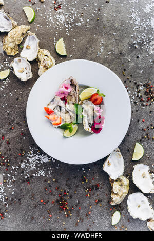 Oysters on a dish decorated with flowers on a gray background