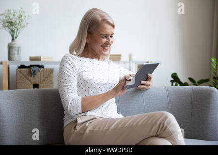 Smiling mature woman using computer tablet at home Stock Photo