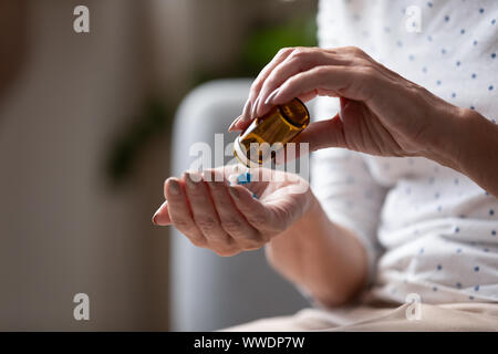 Close up mature woman taking out pills from bottle Stock Photo