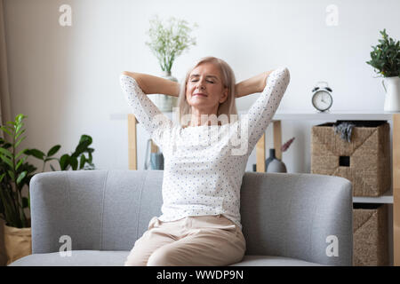 Happy relaxed older woman sitting leaning back on couch Stock Photo