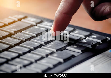 Businessman presses a Enter button on the black keyboard with sunlight Stock Photo